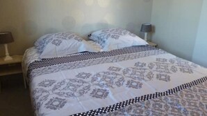 Ein ordentlich bezogenes Bett mit gemusterten Bettwäsche, einer Nachttischlampe und einem Nachttisch.