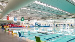 An indoor swimming pool with multiple lanes, colorful chairs, and a high ceiling with structural beams. - Modern waterfront luxury escape near Shepparton (Mooroopna)
