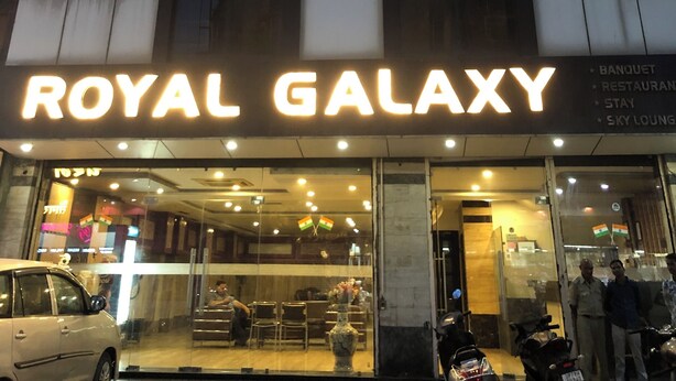A building with a sign reading "ROYAL GALAXY" and a list of amenities including a banquet, restaurant, stay, and sky lounge. - Hotel Royal Galaxy (Kanpur)