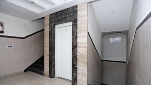 A modern interior with a marble accent wall, a white door, and a tiled floor. - Hotel Royal Galaxy (Kanpur)