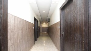 A hallway with wooden walls and doors, leading to a room with a tiled floor and a ceiling light. - Hotel Royal Galaxy (Kanpur)