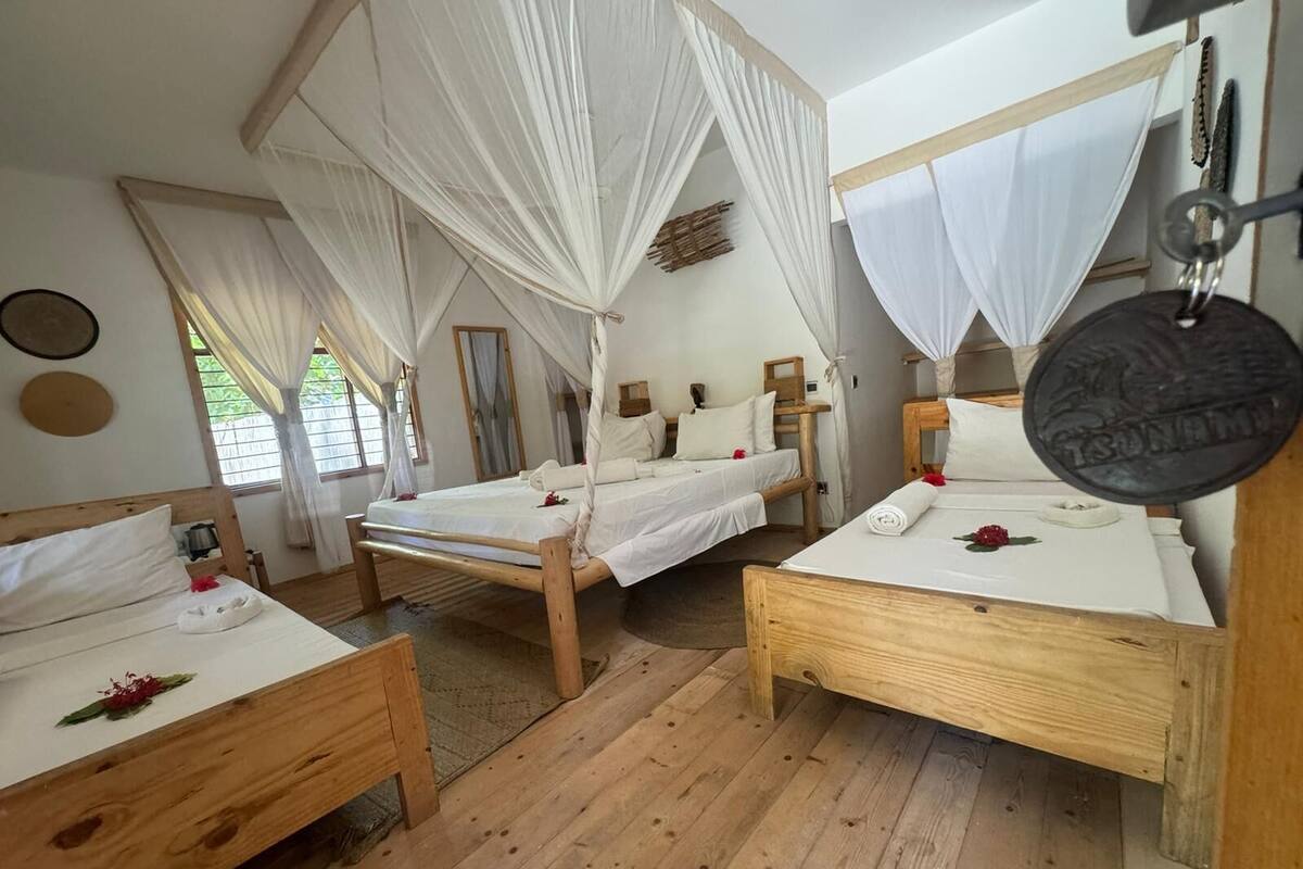 Ein Zimmer mit zwei hölzernen Betten, jeweils mit Baldachin, weißer Bettwäsche und einem kleinen Tisch.