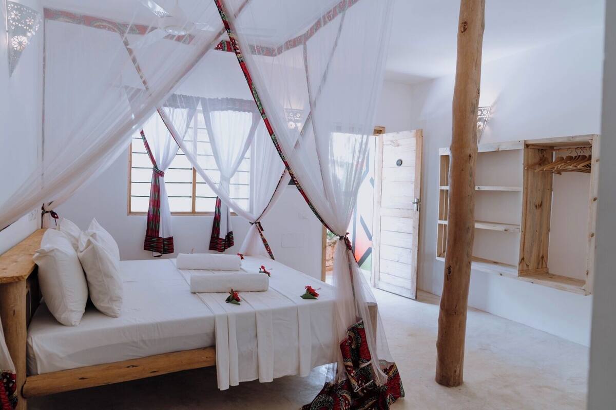 Ein Bett mit Baldachin, Kissen und einem kleinen Tisch.