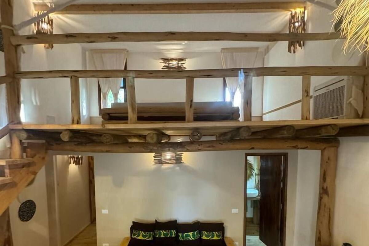 Ein gemütliches Zimmer mit einem Etagenbett, einem kleinen Holztisch und einer gewebten Matte.