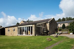 A stone building with large windows and a sloped roof.