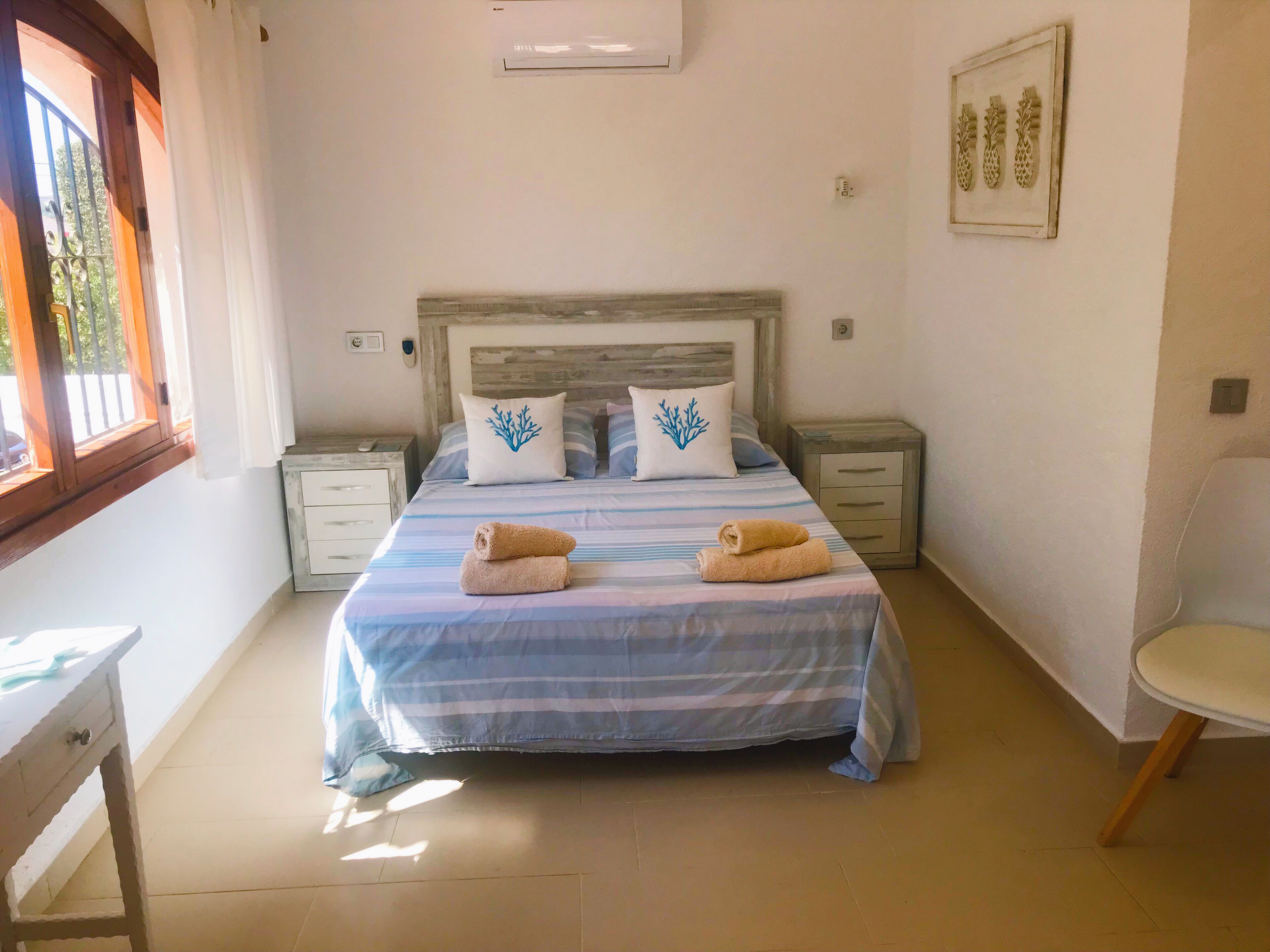 A bedroom with a bed, two nightstands, a chair, and a window.