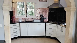Une cuisine avec des meubles blancs, une cuisinière noire et un dosseret carrelé.