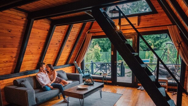 A cozy loft-style room with a wooden interior, a sofa, a coffee table, and a staircase leading to an outdoor area. - Sapanca Saklı Bungalov (Sapanca)
