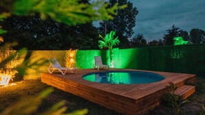A swimming pool with two lounge chairs and a small fire feature. - Sapanca Saklı Bungalov (Sapanca)