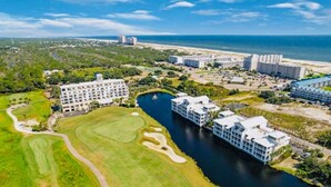 Un complejo turístico costero con varias construcciones, un campo de golf y una masa de agua.