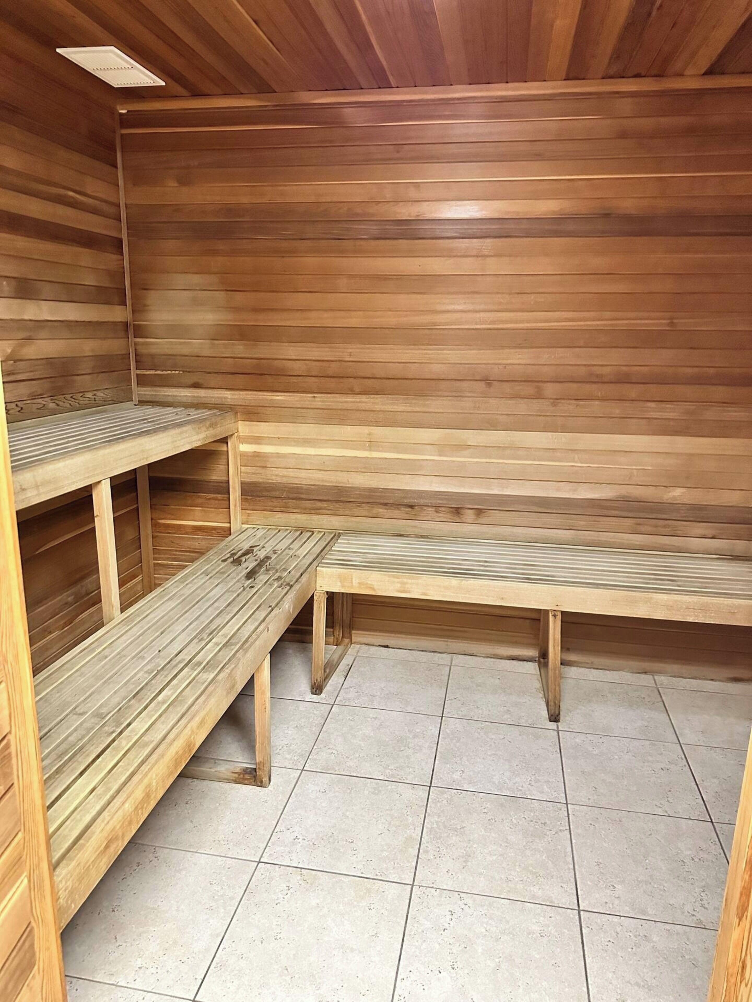 Una sala de sauna con bancos de madera y suelo de baldosas.