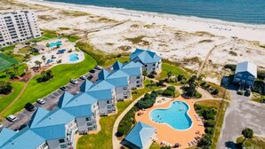 Un complejo turístico con varias edificaciones, una piscina y una playa.