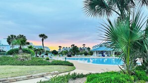 Un resort con piscina, palmeras y vistas al atardecer.