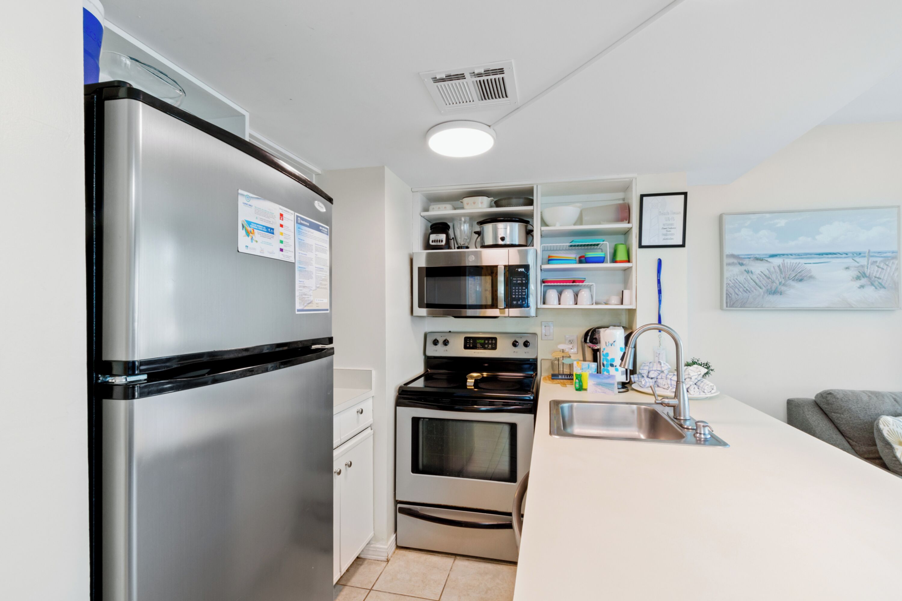 Eine kompakte Küche mit Edelstahl-Kühlschrank, Mikrowelle, Backofen und Spüle.