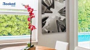 Una mesa de comedor de madera con una orquídea en maceta y una cesta tejida. En la pared, una obra de arte urbana en blanco y negro.