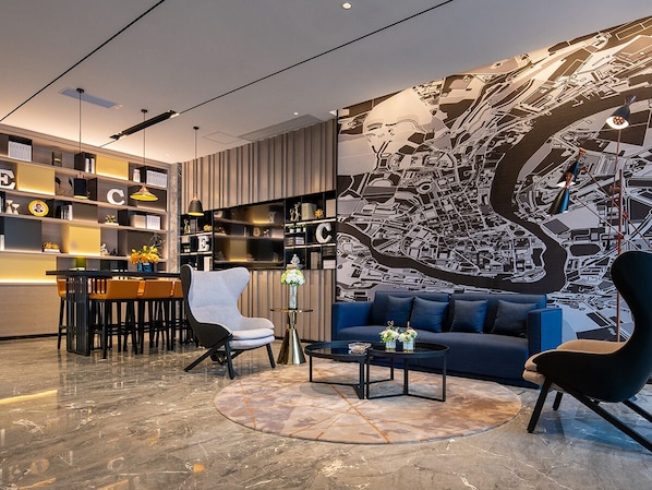 A modern living room with a blue sofa, a white armchair, and a dining area with a table and chairs. There is a large wall mural and a bookshelf with decorative items. - yishangjiudianheyuanlongchuandian (Heyuan)