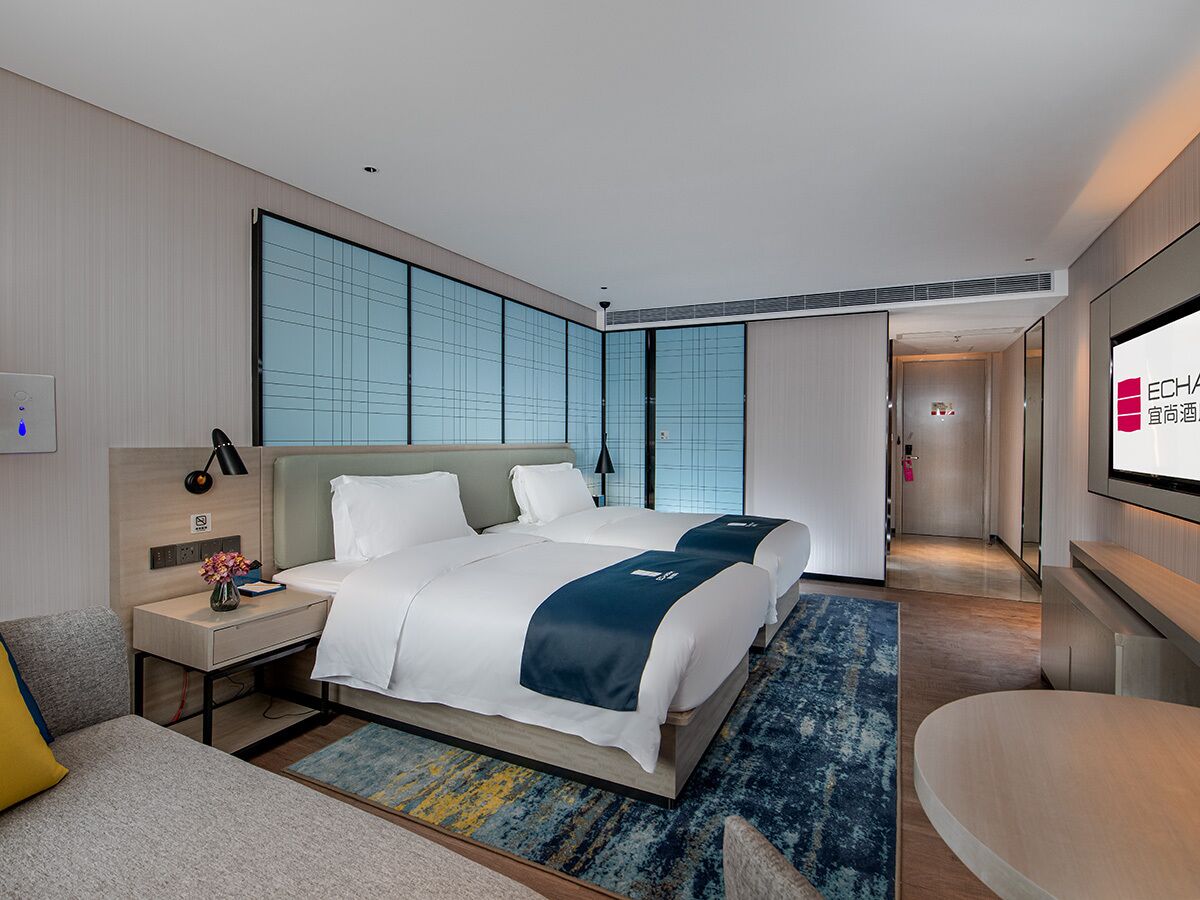 A hotel room with a large bed, a desk, a chair, and a TV.
