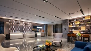 Un vestíbulo moderno con recepción, zona de estar y bar.