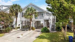 A two-story house with a balcony, a covered porch, and a front yard with a palm tree. - 'A Shore Thing' - Pool - North Myrtle Beach! (North Myrtle Beach)