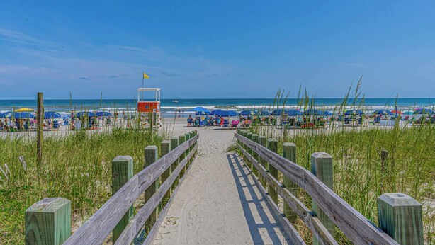 A beach pathway leading to beach umbrellas and beachgoers. - 'A Shore Thing' - Pool - North Myrtle Beach! (North Myrtle Beach)