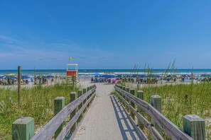 Un sentiero sulla spiaggia che porta a ombrelloni e bagnanti.