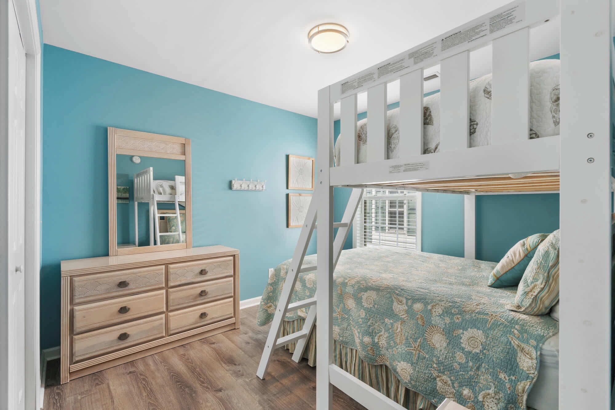 Um quarto com beliche, cômoda, escada e espelho.