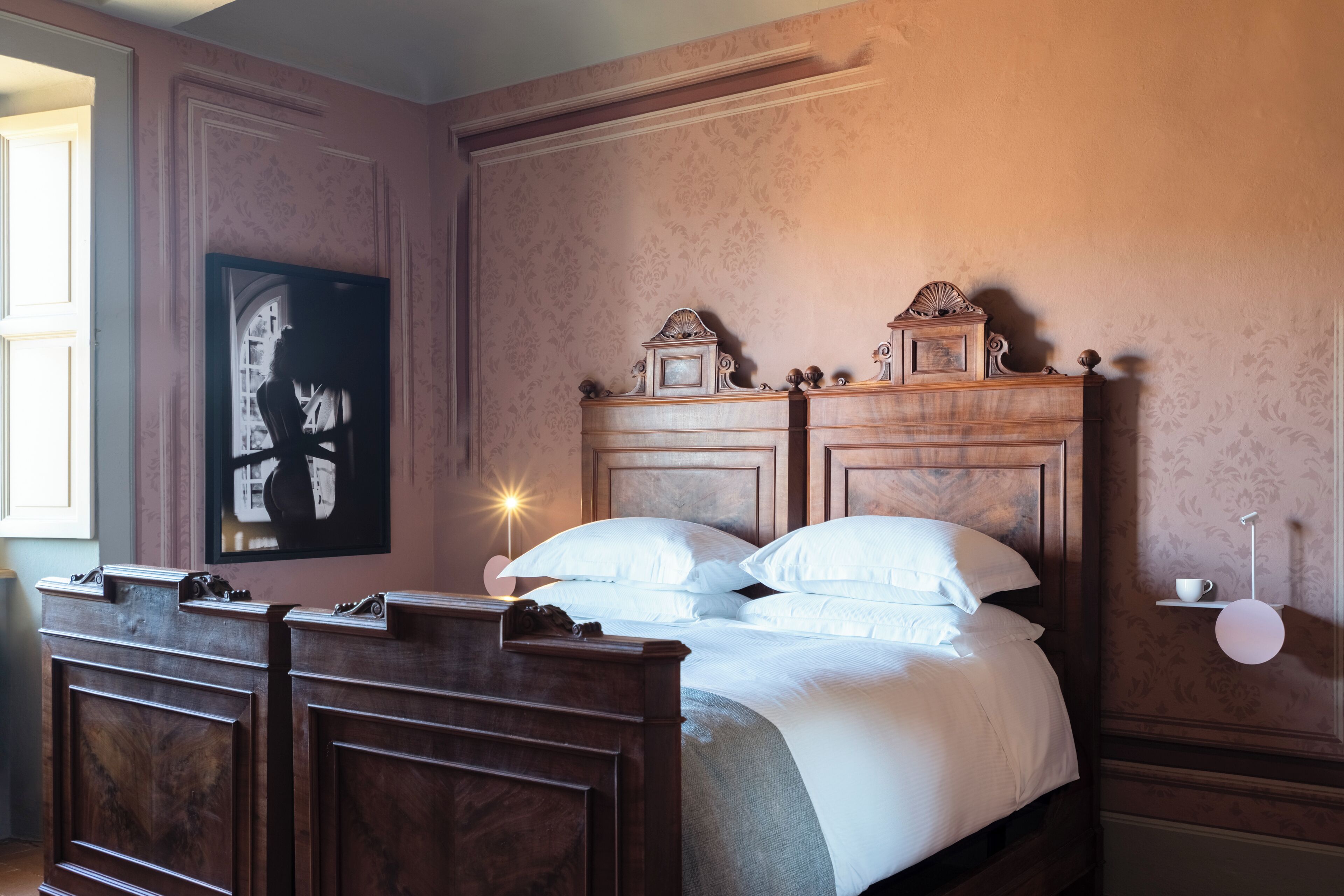 A bedroom with a wooden bed, a nightstand, a framed picture on the wall, and a bedside table with a lamp.