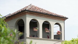 A two-story building with a tiled roof, arched balconies, and flower boxes. - Luxury Langhe Pool Vigne Di Fagnano (Santo Stefano Belbo)