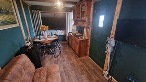 A cozy room with a wooden dining table, chairs, a sofa, and a cabinet. - Sea View hut Sleeps 4/6 (Holyhead)