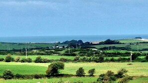 A coastal landscape with green fields, a beach, and a distant view of the sea. - Sea View hut Sleeps 4/6 (Holyhead)