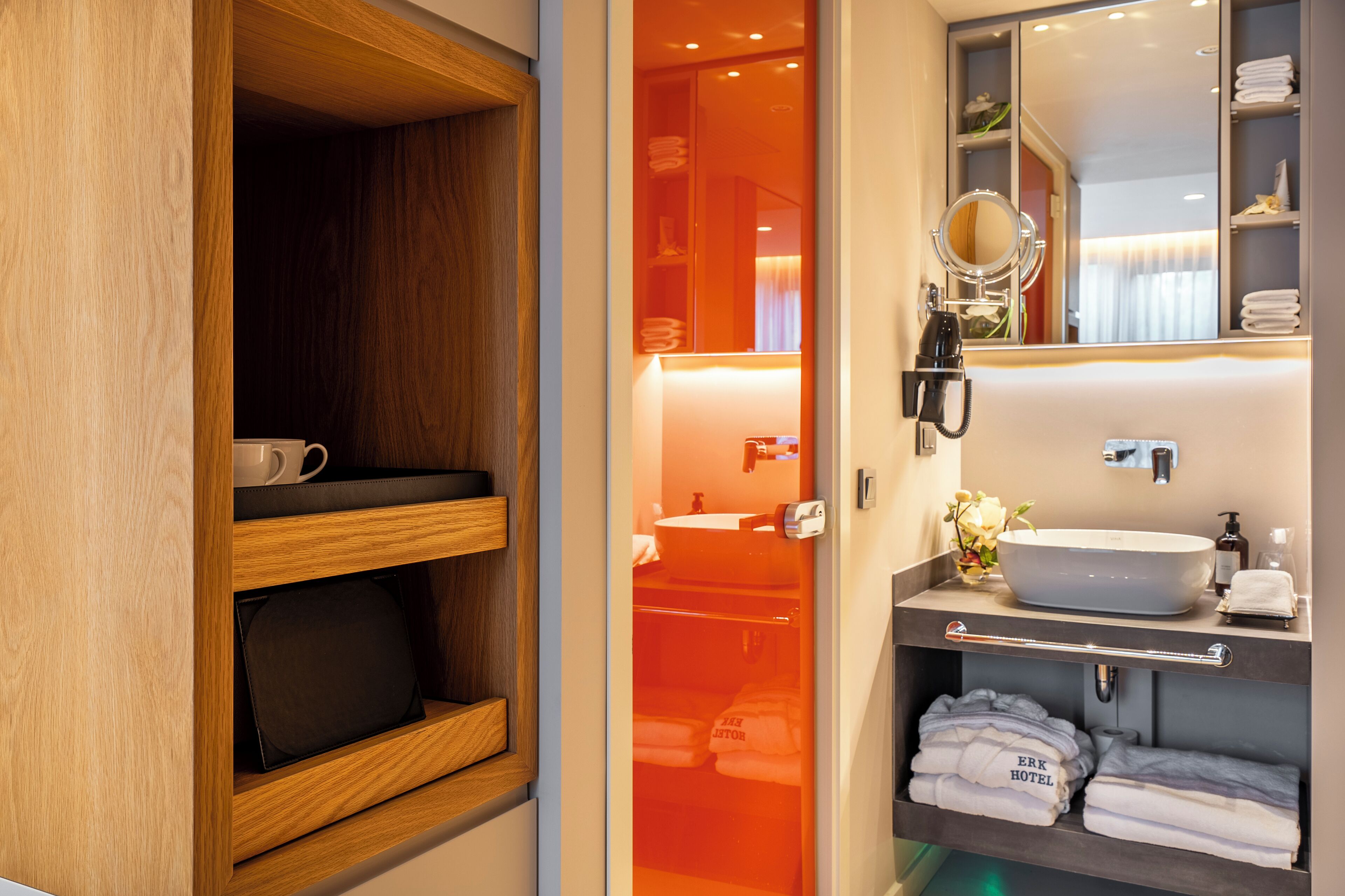 A hotel bathroom with a wooden vanity, a large mirror, a sink, and neatly folded towels.