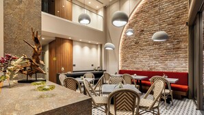 Ένα εστιατόριο με τοίχο από τούβλα, ξύλινη οροφή και καρέκλες από μπαμπού.