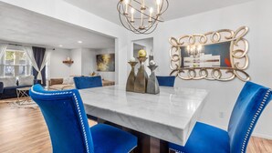 A modern dining area with a marble table, blue upholstered chairs, and a decorative mirror. - Fox Creek Hideaway | Marcel Stays (Belleville)