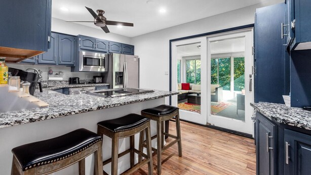 A modern kitchen with granite countertops, stainless steel appliances, and wooden stools. - Fox Creek Hideaway | Marcel Stays (Belleville)