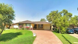 Une maison de plain-pied avec un toit en tuiles, une allée menant à l’entrée et une pelouse bien entretenue.