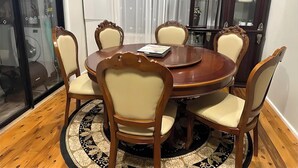 Un coin repas comprenant une table ronde, six chaises et un tapis à motifs.