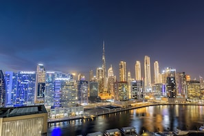 A nighttime cityscape with illuminated skyscrapers and a waterfront. - Waves - Elegant Studio Retreat in Dubai’s Business Bay  (Dubai)