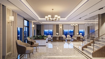 Un lobby amplio con techo alto, candelabros modernos y un área de descanso con sofás y sillones.