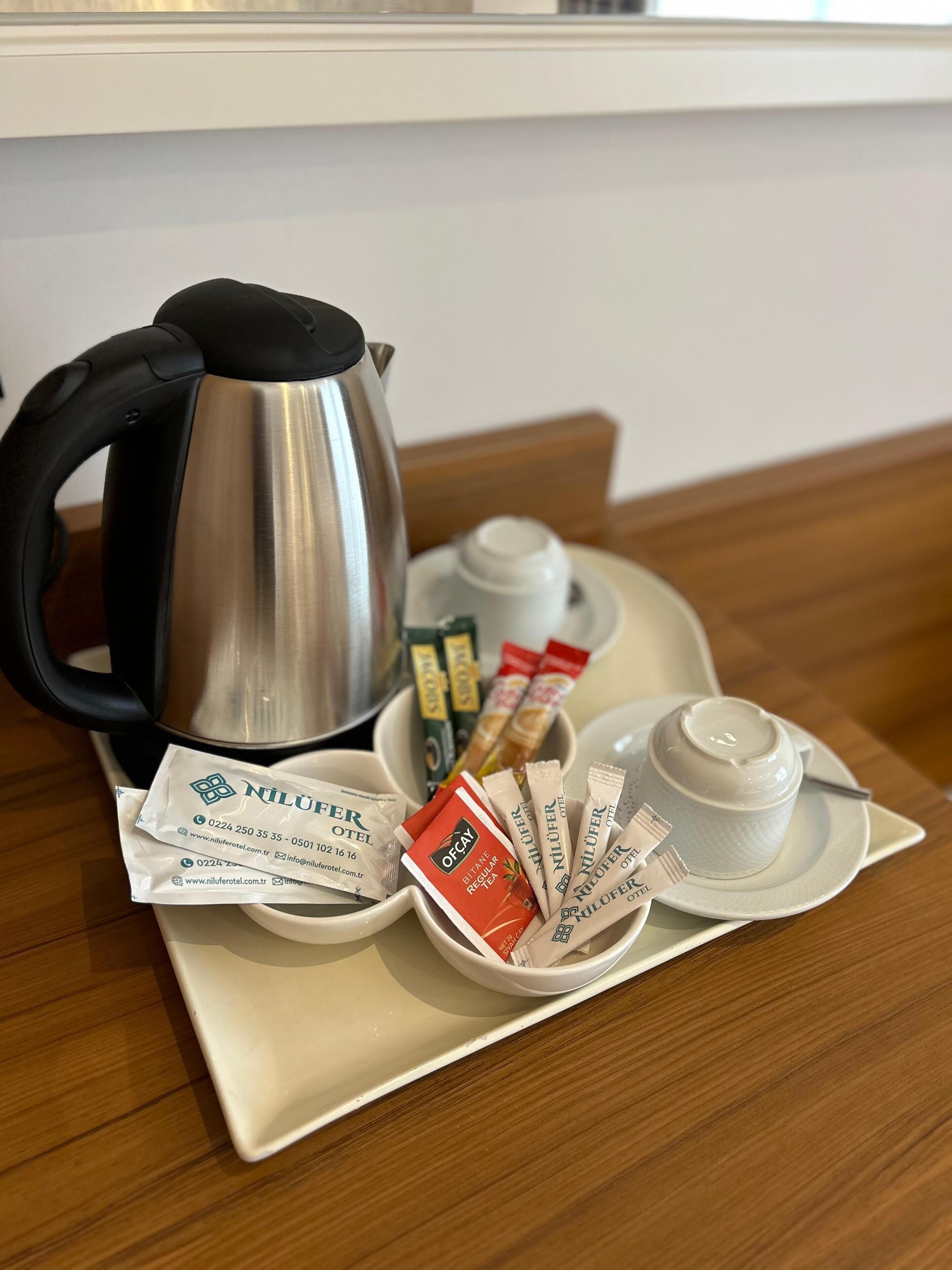 A tray with a coffee maker, tea packets, and a cup on a wooden table.
