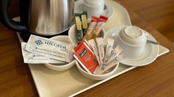 Una bandeja con cafetera, bolsitas de té y una taza sobre una mesa de madera.