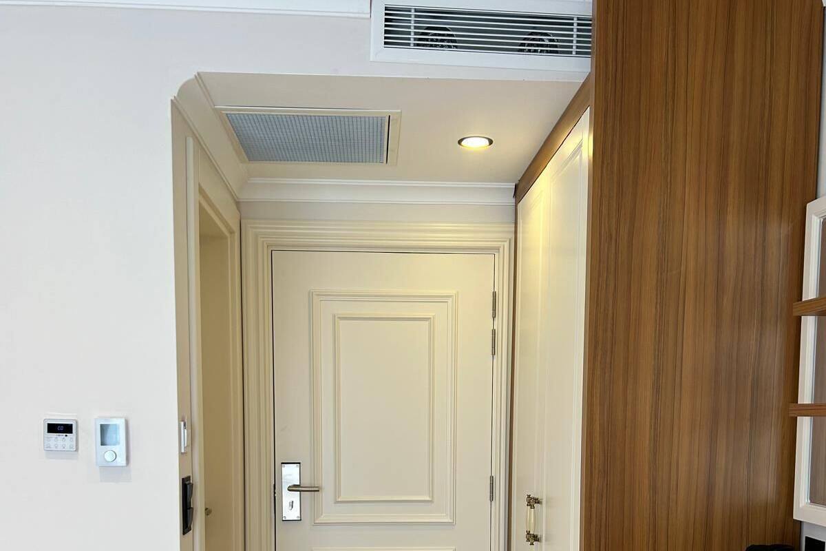 A hallway with a wooden wardrobe, a bed, and a coffee station.