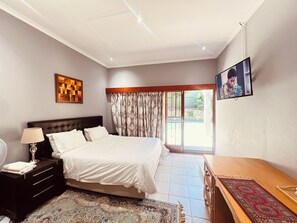 Een slaapkamer met een bed, nachtkastje, lamp, televisie en uitzicht op het landschap.