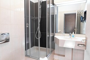 Eenvoudige tweepersoonskamer | Badkamer | Een douche, een haardroger, handdoeken, zeep