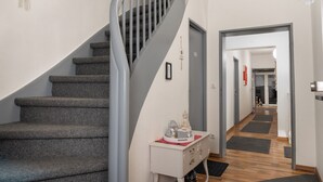 Een trap met een metalen leuning die uitkomt op een plateau. Er staat een klein tafeltje met een decoratieve object erop.
