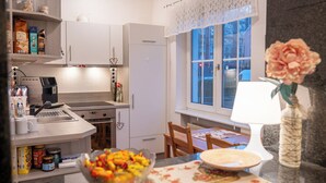 Een moderne keuken met witte kasten, een ingebouwde oven en een eethoek met tafel en stoelen.