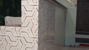 Una recepción con un diseño de patrón geométrico, una mampara de vidrio y suelo de baldosas.