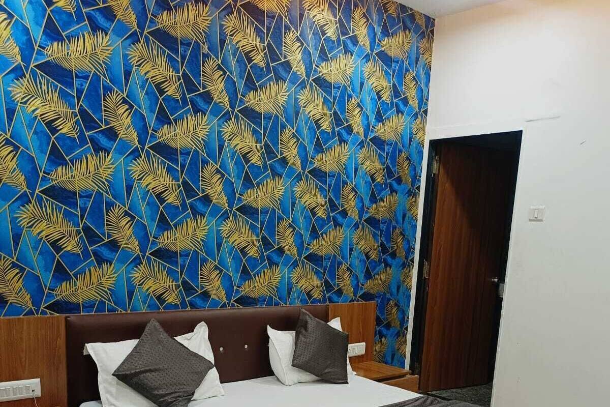 Une chambre d’hôtel avec un grand lit, une table de chevet en bois, un bureau et un mur décoré d’un motif.