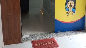 Entrada de un hotel con un cartel que dice 'Welcome to Hotel Arotel', un mostrador de recepción y un interior moderno con un sofá y ventilador de techo.