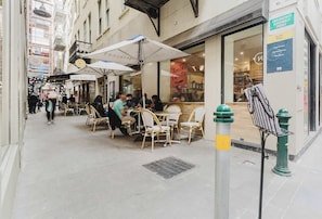 An outdoor café with tables and chairs, a visible entrance to a building, and a green fire hydrant.