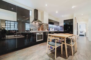 Uma cozinha moderna com uma ilha central, eletrodomésticos embutidos e um espaço de jantar com cadeiras de madeira.